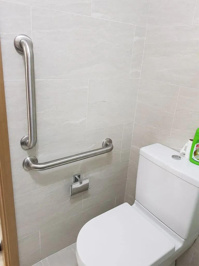 Banheiro adaptado com barras de apoio.