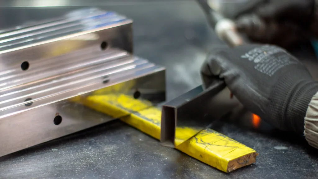 Colaborador da RR Inox e Ferragens cortando peça de aço inox para confeccionar acessórios para vidro.